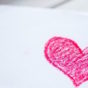 Piece of paper with a heart drawn in red crayon