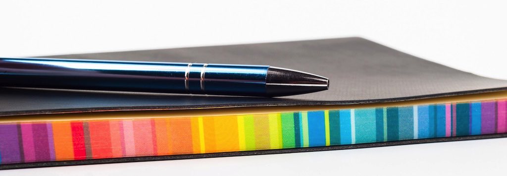 Pen resting on a notebook with multicoloured pages