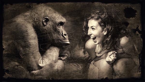 Woman sitting next to an ape and laughing